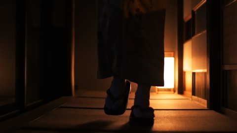 Slow motion of traditional Japanese house ryokan with tatami mat floor, shoji sliding paper doors and woman in kimono, geta shoes tabi socks front walking in corridor hall room