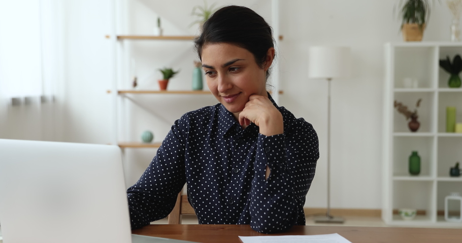 Attractive Indian businesswoman working on laptop sit at workplace at home or office room. Develop start up, search and create new fresh ideas, think over business plan texting on portable computer | Shutterstock HD Video #1063847035