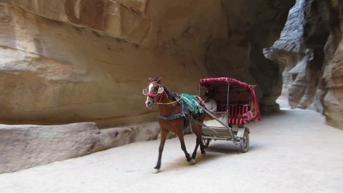 PETRA, JORDAN – MAY 17, 2018: Horse carriage passing through the stone canyon of Siq in the Unesco heritage site of Petra 