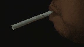 Man smoking cigarette on black background, HD Clip.