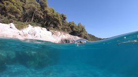 Underwater split line video of beautiful caves with deep turquoise sea and Pine trees of Kastani beach, Skopelos island, Sporades, Greece