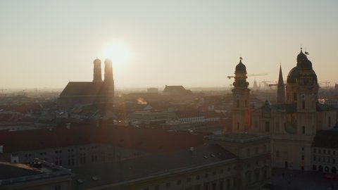 Afternoon Sun peeking behind Frauenkirche Cathedral Silhouette in beautiful Munich Cityscape Establishing Shot on a Winter Day, Aerial slow dolly forwards