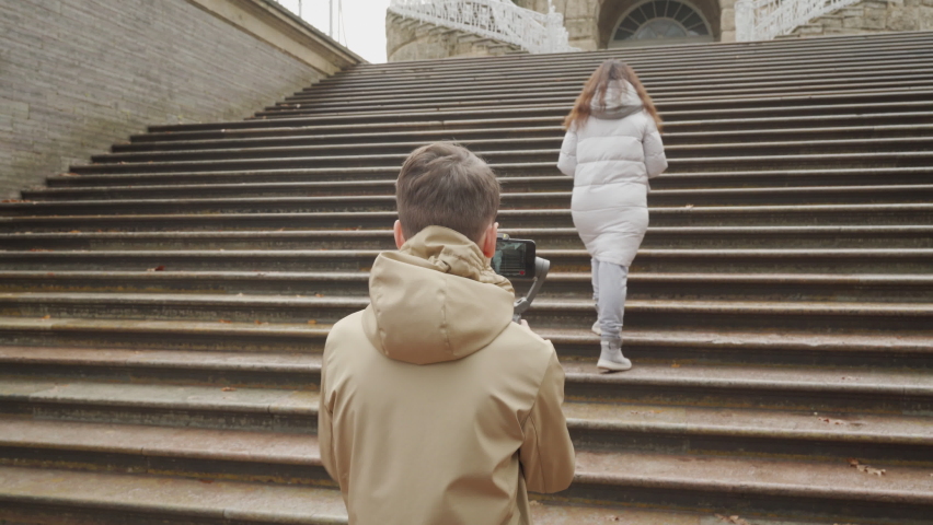 Mother with son walk in autumn park boy with mobile phone camera recording outdoor video blog. Teenager shooting video for travel vlogging. Catherine Park, Tsarskoye Selo, Saint Petersburg, Russia.