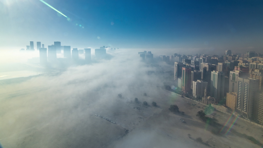 Skylines under the thick fog around towers timelapse of Abu Dhabi at morning, the biggest city of United Arab Emirates. Aerial view of skyscrapers from above after sunrise Royalty-Free Stock Footage #1063873672