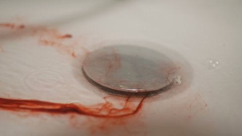 Blood with water flows down the drain hole in the shower. Metaphor.