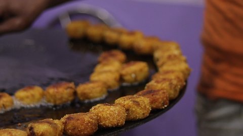 Close up footage of indian street food called chaat, made with deep fried potatoes. delicious potato made dish being fried with selective focus in an indian marriage party. street food Aloo chaat.