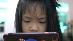 Slow motion scene of A 5-year-old Asian girl sitting and watching a mobile phone.