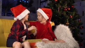 naughty little brother and sister in Christmas hats smile and hug