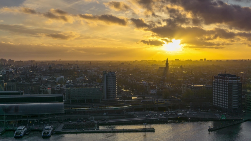 4k time lapse overlooking the historic city center of Amsterdam with the central train station and river IJ during sunset with ferries and trains transporting commuters