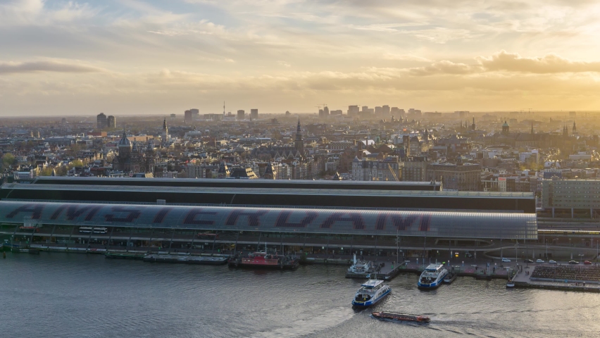 4k time lapse overlooking the historic city center of Amsterdam with the central train station and river IJ during sunset with ferries and trains transporting commuters