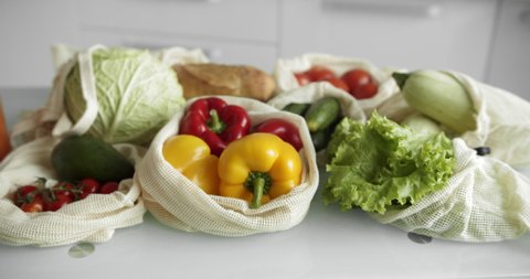 Vegetables, fruits in reusable eco cotton bags on table. Zero waste shopping concept. Plastic free items. Multi-use, reuse, recycle. Eco friendly canvas grocery bag with tomatoes, pepper, bread.