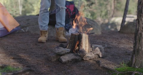 Male legs are standing next to burning bonfire. Tourism and hiking in the mountains 