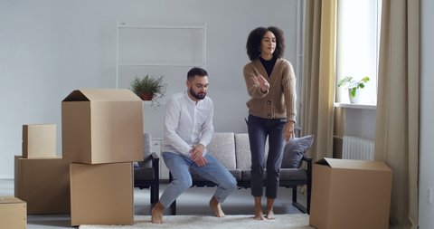Full height filming funny comic young couple friends wife and husband boyfriend and girlfriend dancing move together posing for camera rejoice at buying new home filming real estate, boxes of things