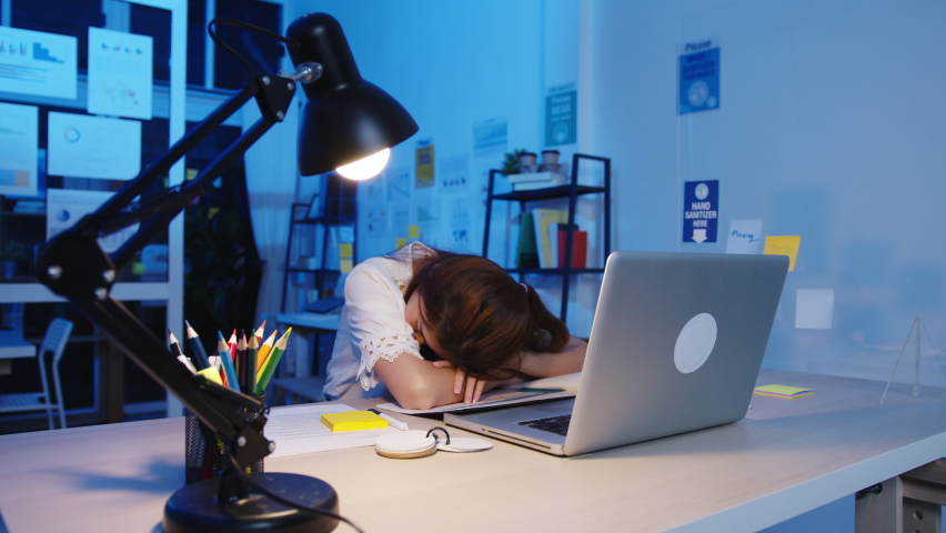 Freelance Asia exhausted lady hard work sleeping at new normal home office. Working from house overload at night, Remotely, self isolation, social distancing, quarantine for corona virus prevention. Royalty-Free Stock Footage #1063895680
