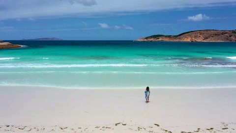 "Girl in a summer dress is running into Hellfire bay near Esperance viewed during a cloudy day, Australia"