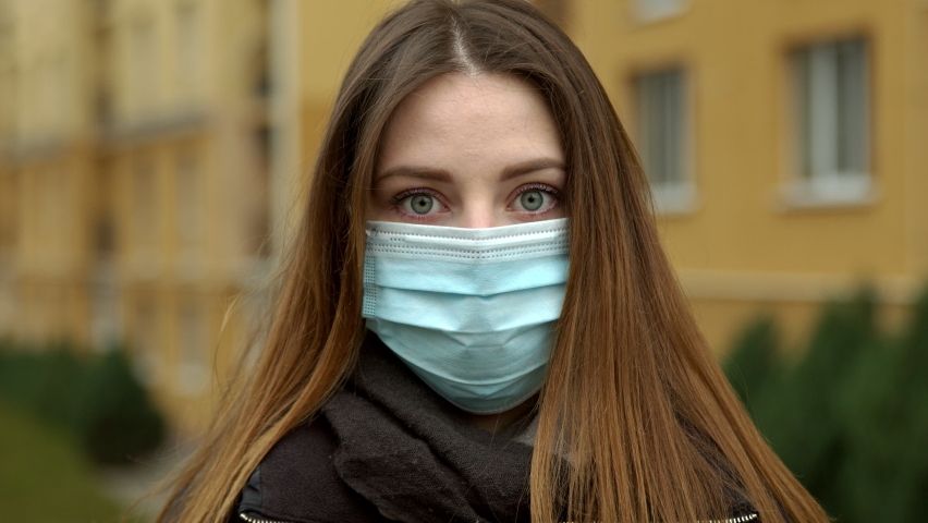 Young white girl with green eyes outdoors puts on a medical mask.4K, Slow motion | Shutterstock HD Video #1063899214