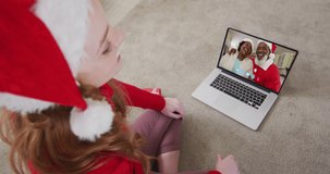Caucasian woman wearing santa hat on laptop video chat during christmas at home. communication with friends and family at christmas during covid 19 pandemic.