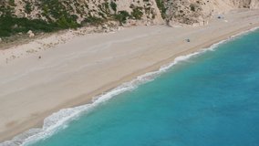 Aerial view of beautiful Milos beach of Lefkada, Ionian island, Greece. Pristine waves breaking the turquoise blue sea on the shore at sunset light.
