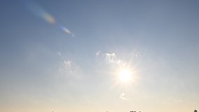 Video of the sun moving across the sky. Dynamic light rays, lens flare effects. Sparkle sun moves across blue cloudy sky. Sunrise and sunset. Nature concept animation. Seamless 4K clip