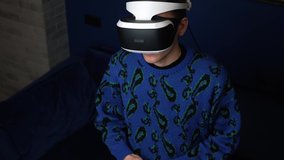 Slow motion scene video of a caucasian man using a VR headset helmet device to play video games at home.