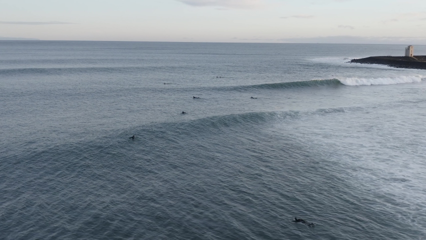 Aerial of surfers swimming towards lineup area behind break, duckdiving Royalty-Free Stock Footage #1063915024