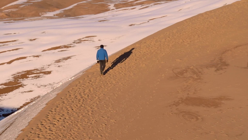 Man walking on sand dunes in slow motion