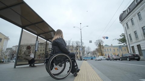 Person with a physical disability waiting for a bus at a bus stop