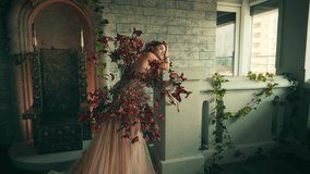 Portrait of beautiful fantasy woman fairy tale queen bride. Princess Girl fashion model in old room castle. Long trendy creative dress decorated with artificial red butterflies. Elegant lady dreaming