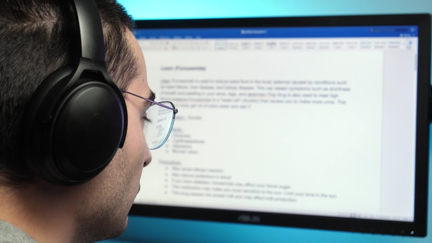 Writing a text in a text editor on a computer monitor wearing headphones at home. freelancer, student concept shot. Royalty-Free Stock Footage #1063929025