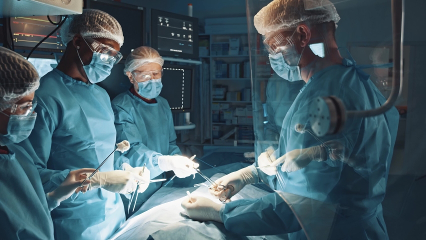 Process of trauma surgery operation. Group of surgeons wearing protective masks brainstorming before the hard operation in operating room with surgery equipment. Medical and saving lifes concept | Shutterstock HD Video #1063930672