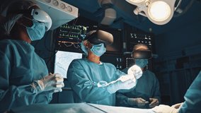 Surgeons wearing augmented reality glasses to perform state of the art surgery in technologically advanced hospital. Doctors and assistants working together in dark operating room standing under lamp - Powered by Shutterstock - Get 15% off with code: PIKWIZARD15