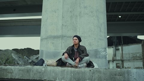 Homeless person feeling cold, sitting under bridge, refugee with nowhere to go