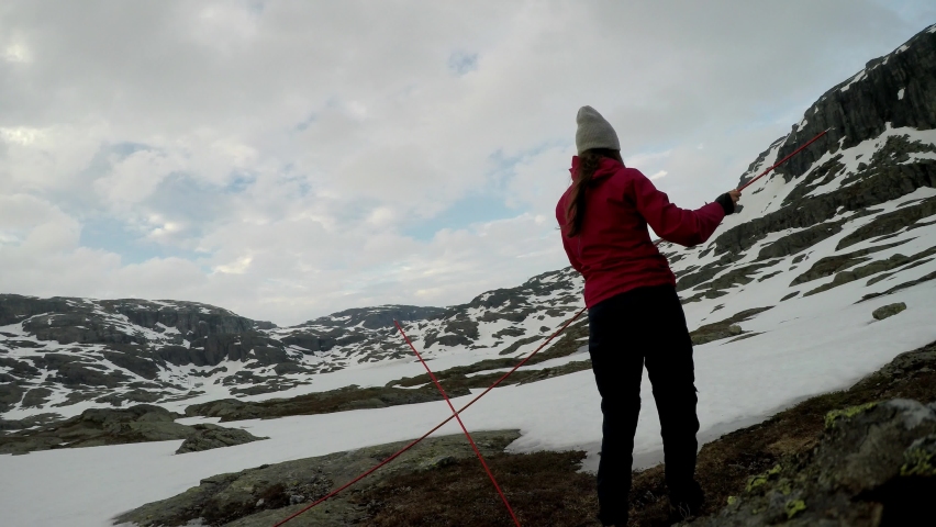 A young couple putting up the tent in the nearby of Trolltunga, Norway. Wild camping in the nature. Couple is having fun. They are surrounded by snow. Winter mountain climbing. Freedom and adventure. 