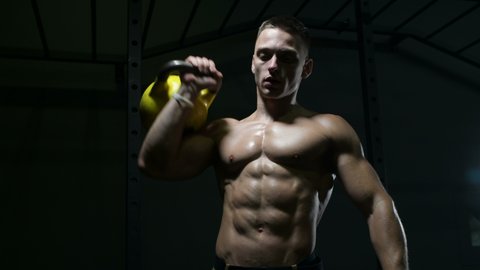 Fitness man at workout in gym pumping up muscles with kettlebell. Fitness and bodybuilding health care concept