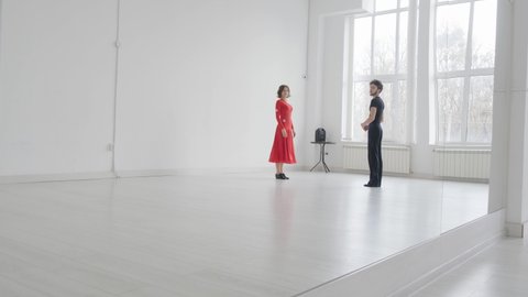 Young beautiful couple studying ballroom dance. A professional ballroom dancing couple dances in a large, bright, white hall