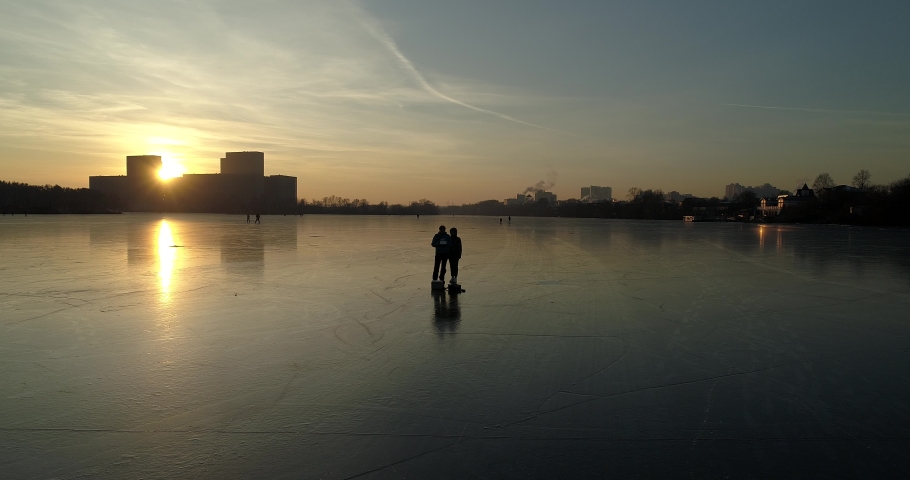frozen river. Pattern of ice on the surface of the water. Background. Two silhouettes of a man stand on the ice. Man and woman together
