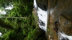 Vertical Video: Small Cascade Waterfall in Mountain River in Tropical Forest. Eco Tourism and Traveling. Huay To Waterfall with Stream Clear Water Among Green Jungle. Travel and Relax in Thailand