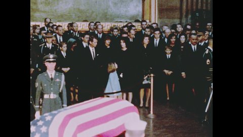 1960s Washington DC: Jackie, Bobby and Caroline Kennedy in crowd near soldier and flag-draped coffin as President Lyndon Johnson and a soldier bring wreath on stand near coffin
