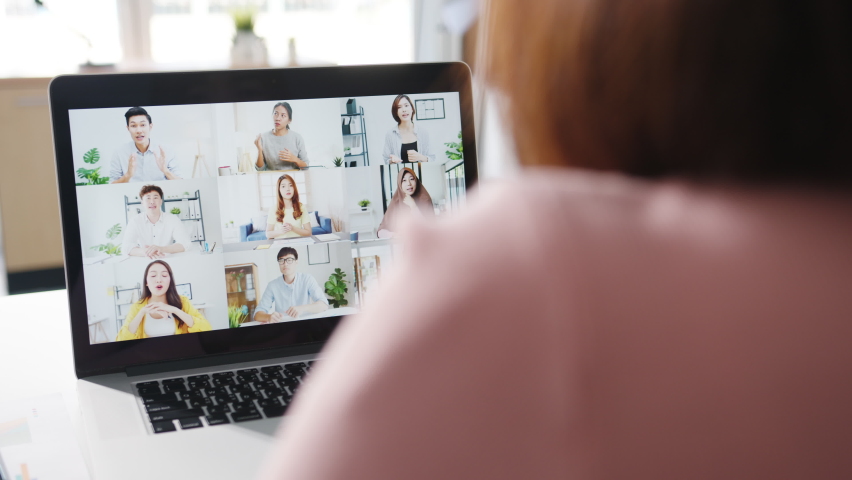 Young Asia businesswoman using laptop talk to colleague about plan in video call meeting while work from home at living room. Self-isolation, social distancing, quarantine for corona virus prevention. | Shutterstock HD Video #1063943689