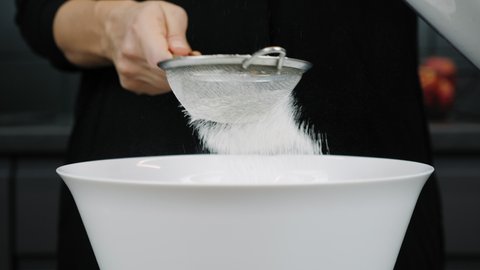 Flour is sifting with sieve. Flour is pouring through sieve. Preparing pizza or bakery
