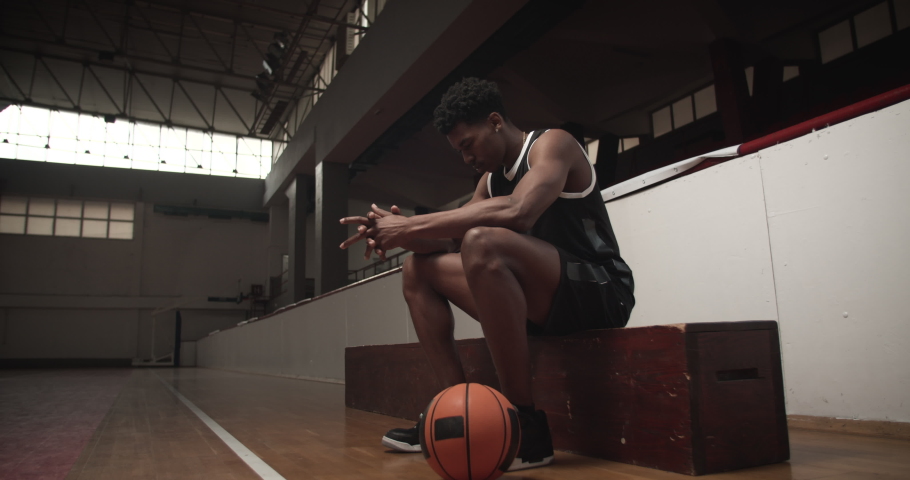 Basketball player sitting on a bench, serious and concentrated Royalty-Free Stock Footage #1063949482