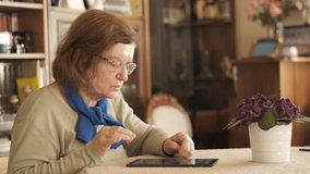Tablet. Senior adult using digital technology device indoors. Touching screen.
