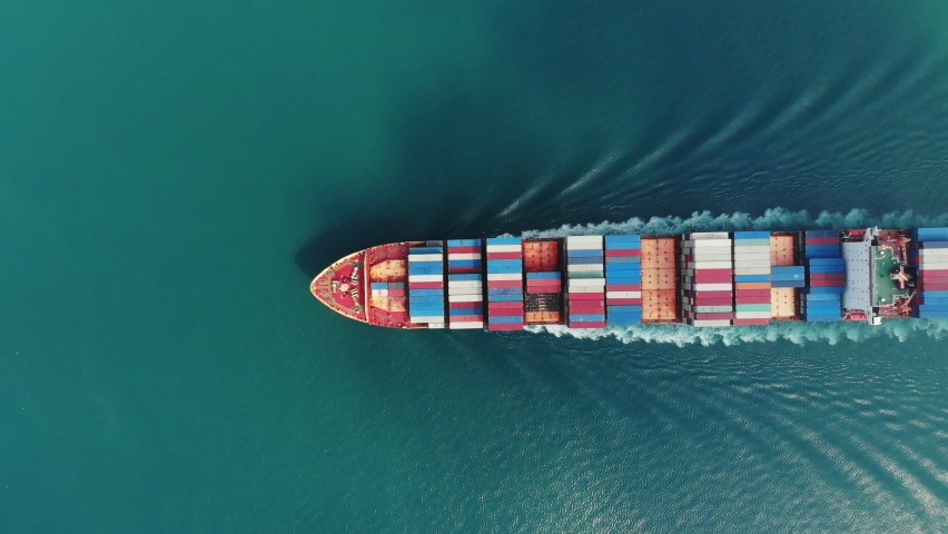 Aerial top view of smart cargo ship carrying container and running very fast for export cargo from container yard port to custom ,Contrail line in the ocean by large ship very fast.  Royalty-Free Stock Footage #1063952977