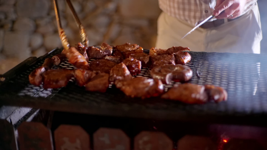Close up on man turning and cutting steak on braai, traditional South African bbq Royalty-Free Stock Footage #1063955941