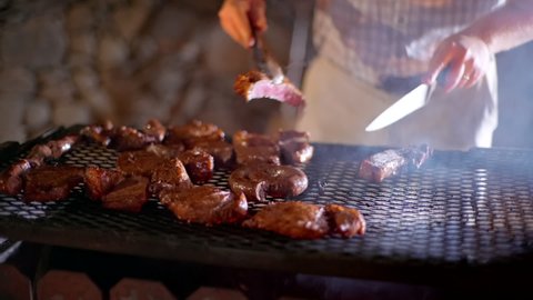 Close up on man turning and cutting steak on braai, traditional South African bbq
