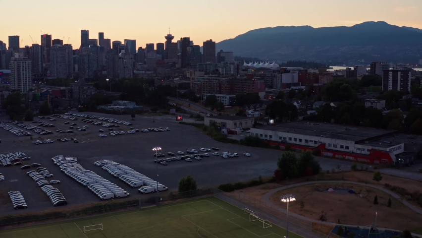 Sunset Drone Aerial shot with football ground and sun setting behind cityscape North Vancouver British Columbia, Canada
