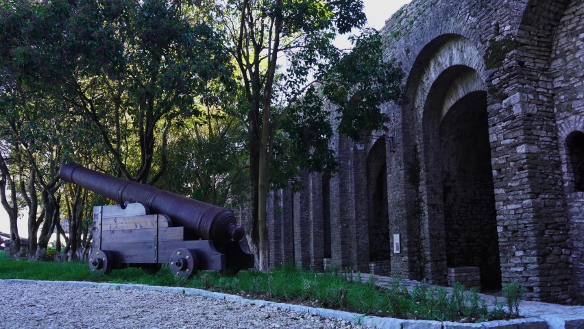 Gun in front of high stone walls outside historic famous castle of Gjirokastra
