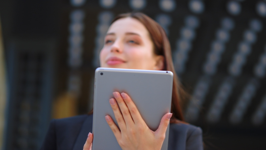 Closeup happy woman face looking tablet screen outdoors. Elegant businesswoman chatting online with digital device outside. Portrait of business woman using tablet computer near office building. | Shutterstock HD Video #1063958455