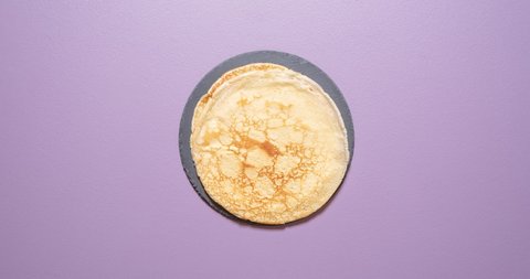 Making crepes stop motion above view on a purple background. Baking french thin pancakes in an iron cast pan. 
