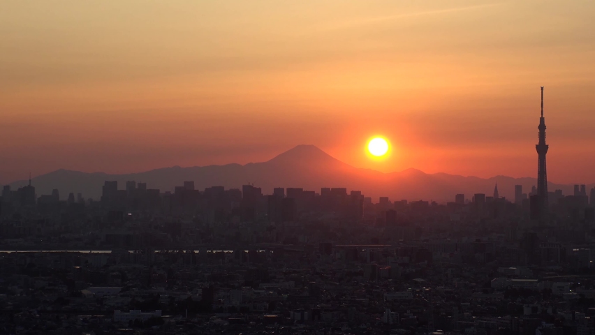 TOKYO, JAPAN : Aerial high angle sunrise CITYSCAPE of TOKYO and MOUNT FUJI. View of rising sun and buildings at downtown area. Japanese city life and nature concept. Time lapse shot night to morning.